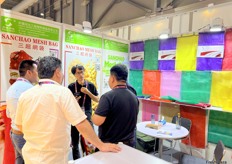 Cicular loom net bags, water loom bags and raschel machine net bags and woven bags are the main products of Sanchao Esh Bag. The company representative is talking with clients at their booth./ 圆织机网袋、水织机网袋、拉舍尔机网袋、编织袋是三超网袋的主要产品。公司代表正在展位上与客户交谈。 