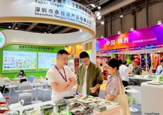 Representative of Shenzhen Yongjia Fresh Produce (left) is talking with visitors at the stand. / 深圳永佳农产品有限公司代表（左）在展位与参观者交谈。 