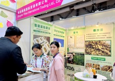 Representatives of Qingdao Yihao International Trading (middle) is talking with a visitor. Fresh giner is their main export product. / 青岛驿昊国际贸易有限公司代表（中）与参观者交谈。新鲜杜松子酒是他们的主要出口产品。